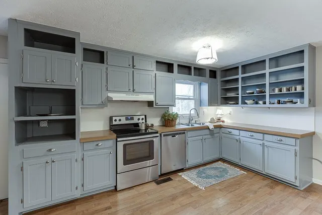 a kitchen with cabinets wooden floor and stainless steel appliances
