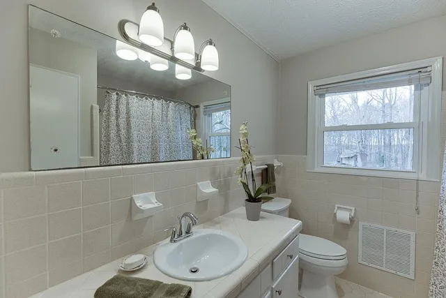 a bathroom with a granite countertop sink a toilet and a mirror