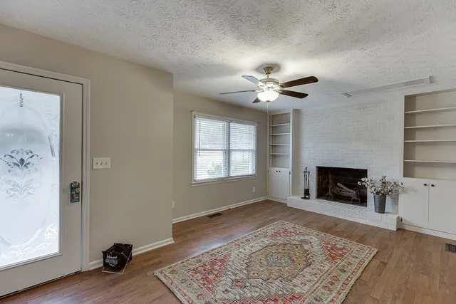 a view of a livingroom with a fireplace a ceiling fan and a fireplace