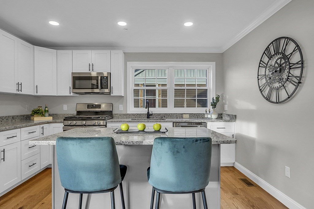 30 Broadway, Unit A Lynn, MA 01904 - Photo 8 of 34 a kitchen with a stove a sink a microwave a dining table and chairs
