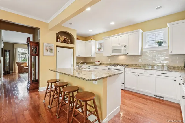 a kitchen with stainless steel appliances granite countertop a stove a sink dishwasher and a refrigerator with wooden floor