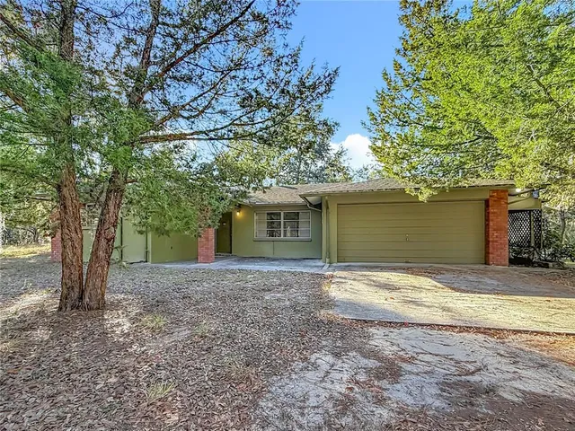 a view of a house with a yard and large tree