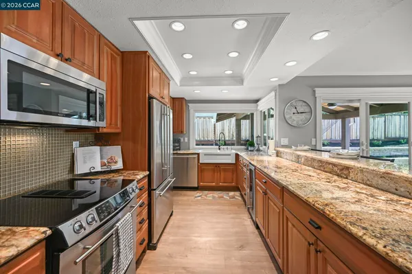 a large kitchen with stainless steel appliances granite countertop a stove top oven a sink dishwasher and microwave oven