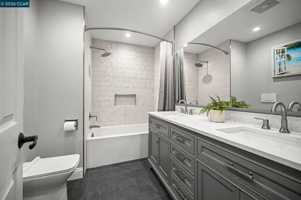 a bathroom with a double vanity sink toilet mirror and bathtub