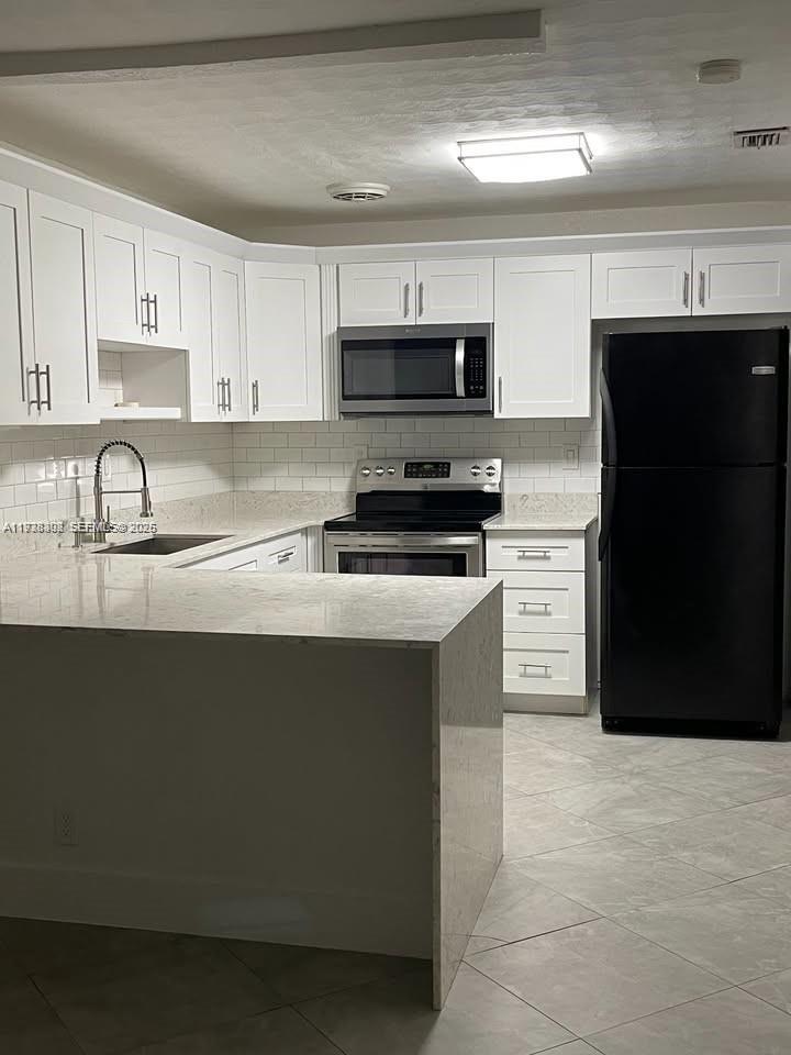 1640 Northeast 33rd Street Pompano Beach, FL 33064 - Photo 3 of 8 a kitchen with stainless steel appliances a sink a stove a microwave and wooden cabinets