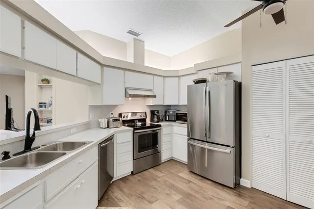 a kitchen with a refrigerator sink and white cabinets
