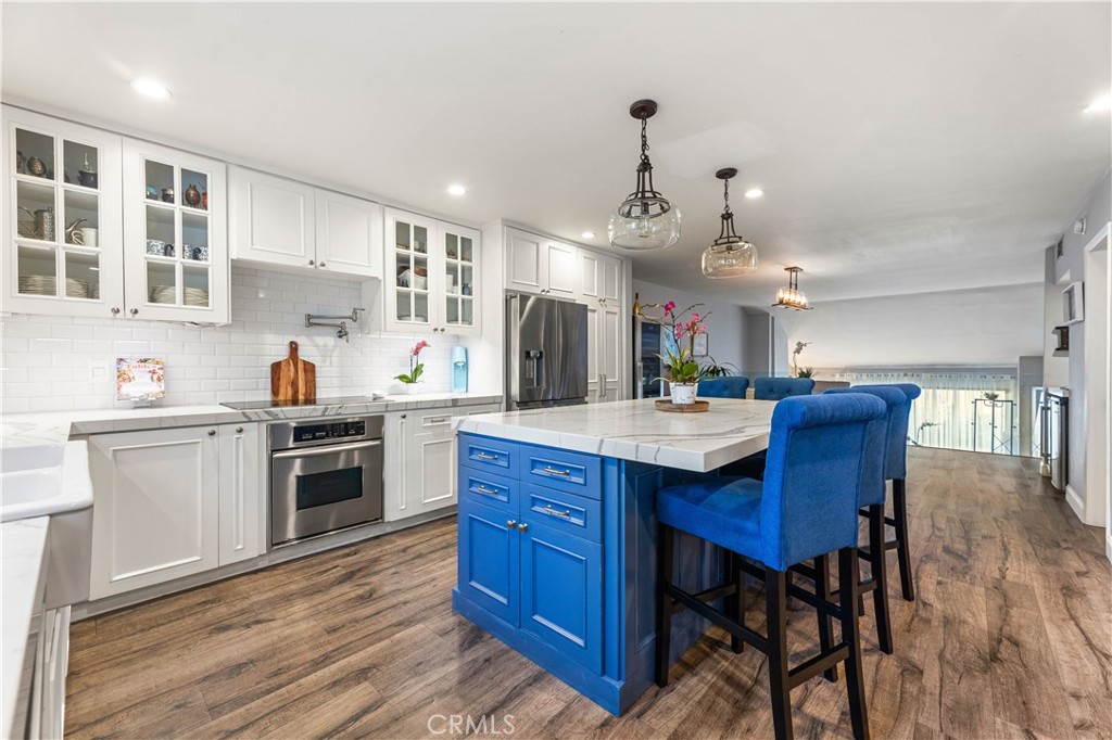 18146 Oxnard Street, Unit 48 Tarzana, CA 91356 - Photo 11 of 52 a kitchen with stainless steel appliances granite countertop wooden floors and wooden cabinets