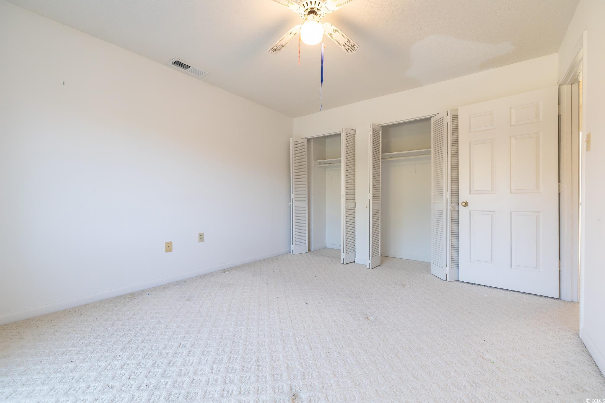 43 Pheasant Loop, Unit 302 Georgetown, SC 29440 - Photo 17 of 38 Unfurnished bedroom with multiple closets, carpet flooring, and a ceiling fan