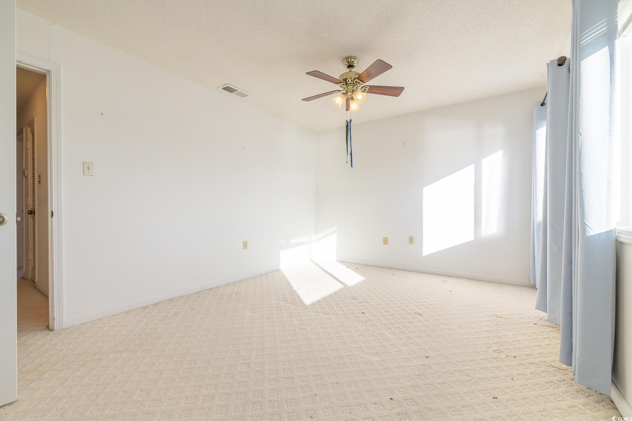 43 Pheasant Loop, Unit 302 Georgetown, SC 29440 - Photo 22 of 38 Spare room with carpet, healthy amount of natural light, a ceiling fan, and a textured ceiling