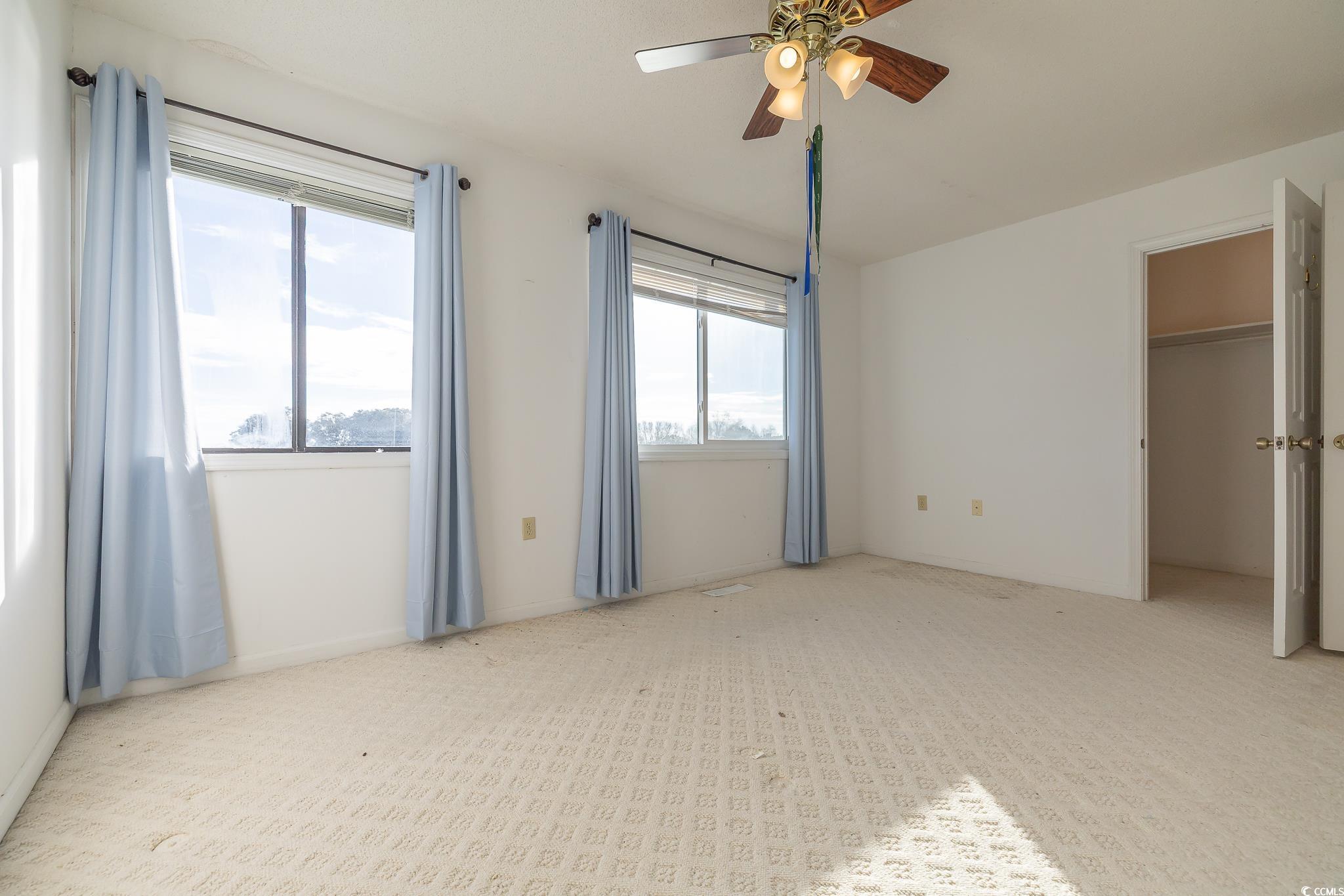 43 Pheasant Loop, Unit 302 Georgetown, SC 29440 - Photo 23 of 38 Unfurnished bedroom with a spacious closet, ceiling fan, and carpet