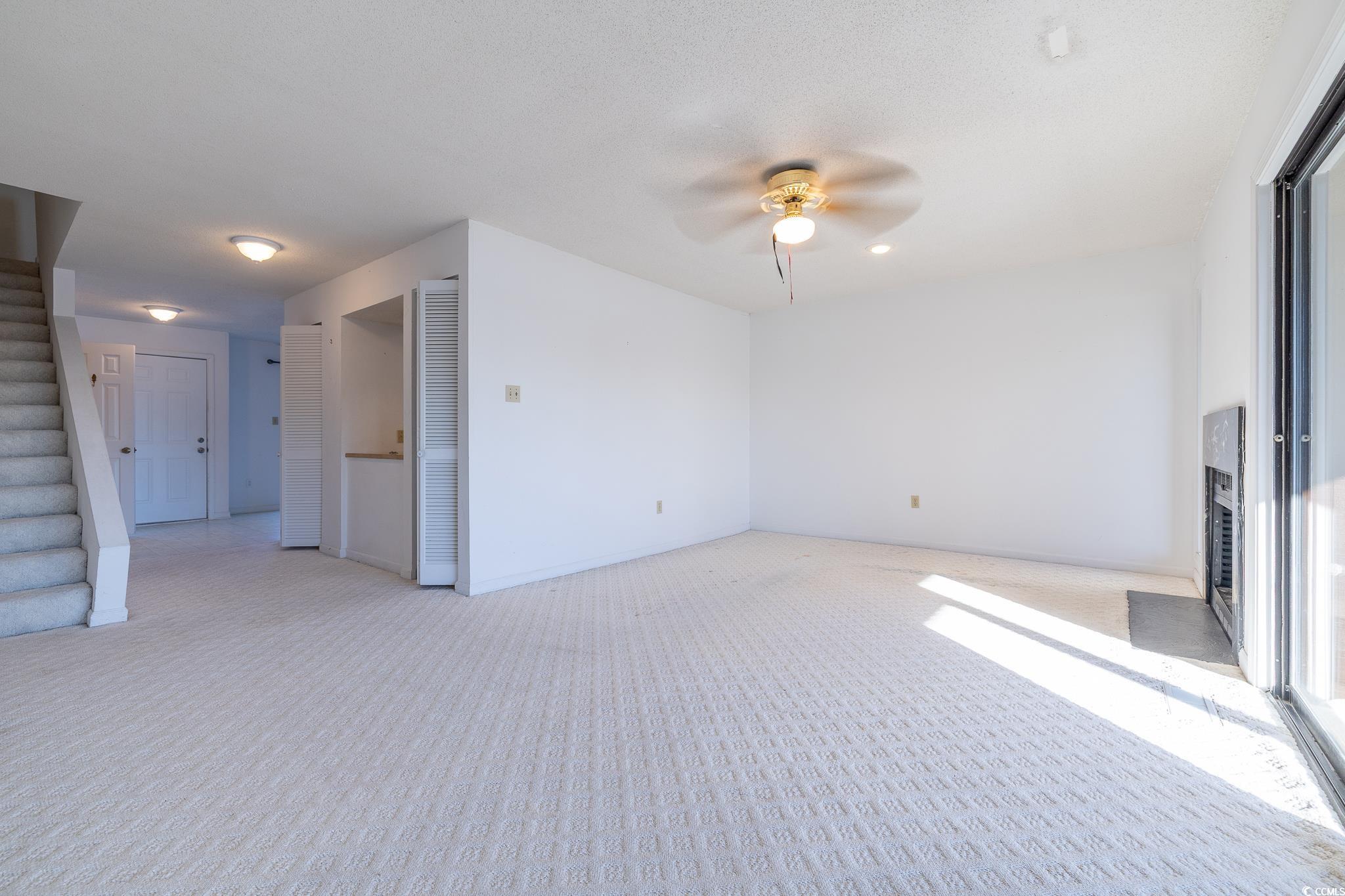43 Pheasant Loop, Unit 302 Georgetown, SC 29440 - Photo 5 of 38 Carpeted empty room with stairway and ceiling fan