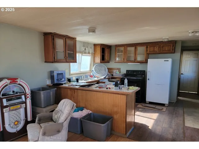 a living room with furniture a flat screen tv and a refrigerator