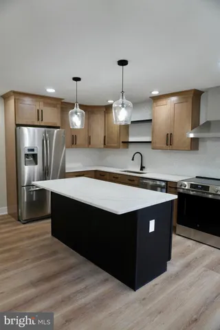 a large kitchen with stainless steel appliances a sink dishwasher a stove and white cabinets with wooden floor