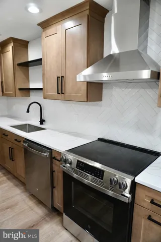 a kitchen with stainless steel appliances a stove a refrigerator a sink and a chandelier