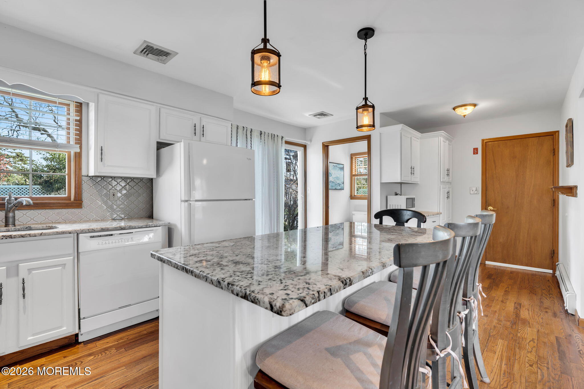 1706 Bay Avenue Point Pleasant, NJ 08742 - Photo 10 of 34 a kitchen with stainless steel appliances granite countertop a sink a refrigerator a stove a dining table and chairs with wooden floor