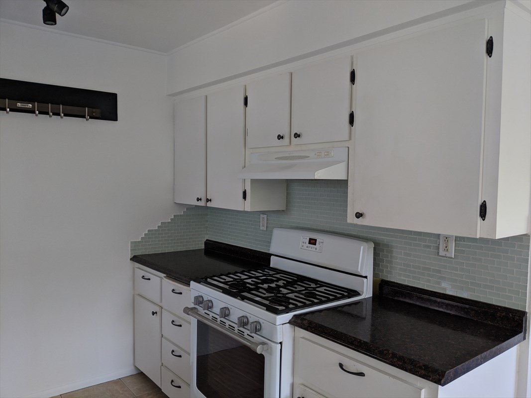 4547 Panihi Road Kapaa, HI 96746 - Photo 9 of 28 a kitchen with granite countertop white cabinets and black stove top oven