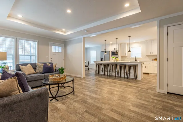 a living room with furniture a kitchen view and a window