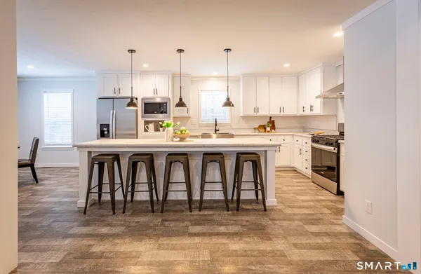 a kitchen with stainless steel appliances granite countertop a stove top oven a sink dishwasher and white cabinets