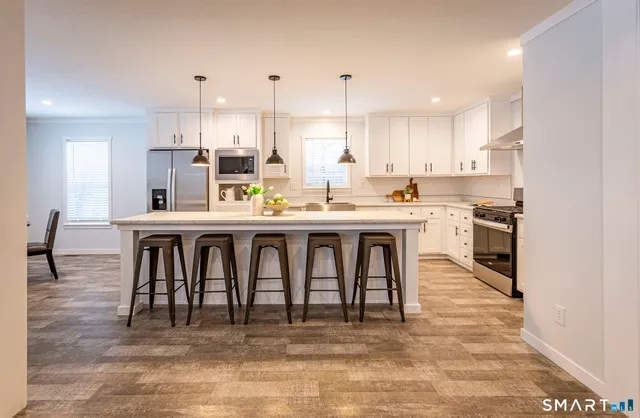 a kitchen with stainless steel appliances granite countertop a stove top oven a sink dishwasher and white cabinets