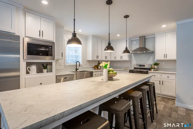 a kitchen with stainless steel appliances granite countertop a sink a stove and a wooden floors