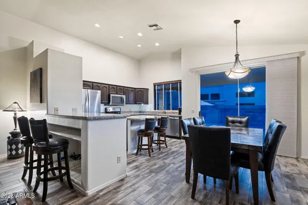 a dining room with wooden floor a chandelier a wooden table and chairs