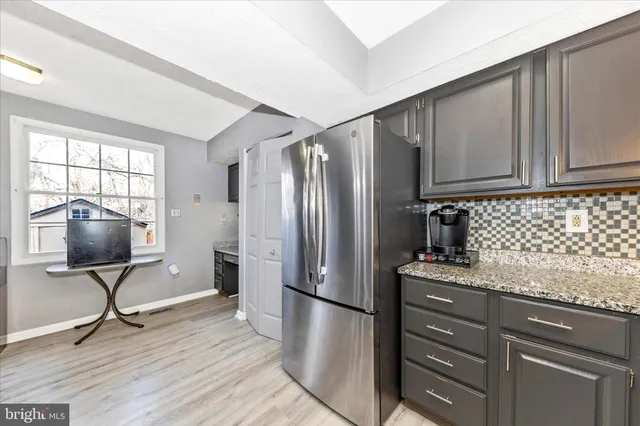 a kitchen with granite countertop a refrigerator stove and wooden floor