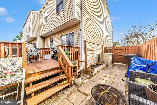 a view of a patio with couches and table and chairs with wooden floor and fence