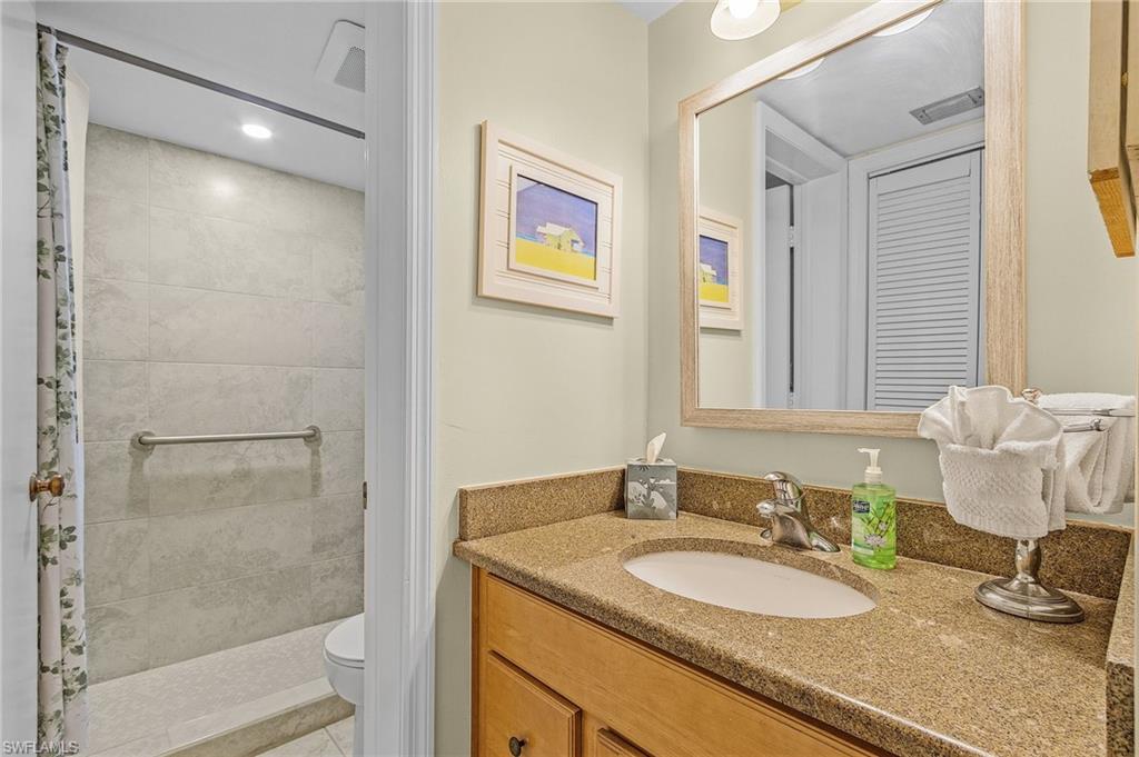 600 Neapolitan Way, Unit 349 Naples, FL 34103 - Photo 21 of 34 a bathroom with a granite countertop sink and a mirror