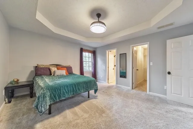 a spacious bedroom with a bed and a dresser next to a window