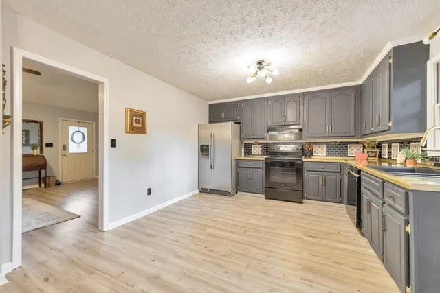 a kitchen with granite countertop a refrigerator sink and cabinets