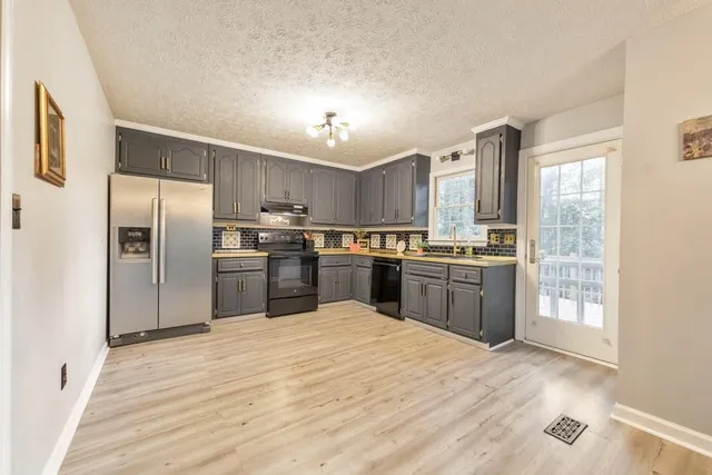 a kitchen with stainless steel appliances a table chairs in it and wooden floors