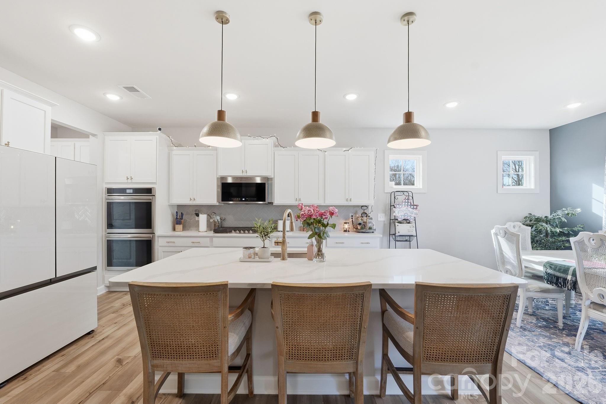 3911 Horsham Street Fort Mill, SC 29707 - Photo 15 of 41 a kitchen with stainless steel appliances kitchen island granite countertop a dining table chairs and white cabinets