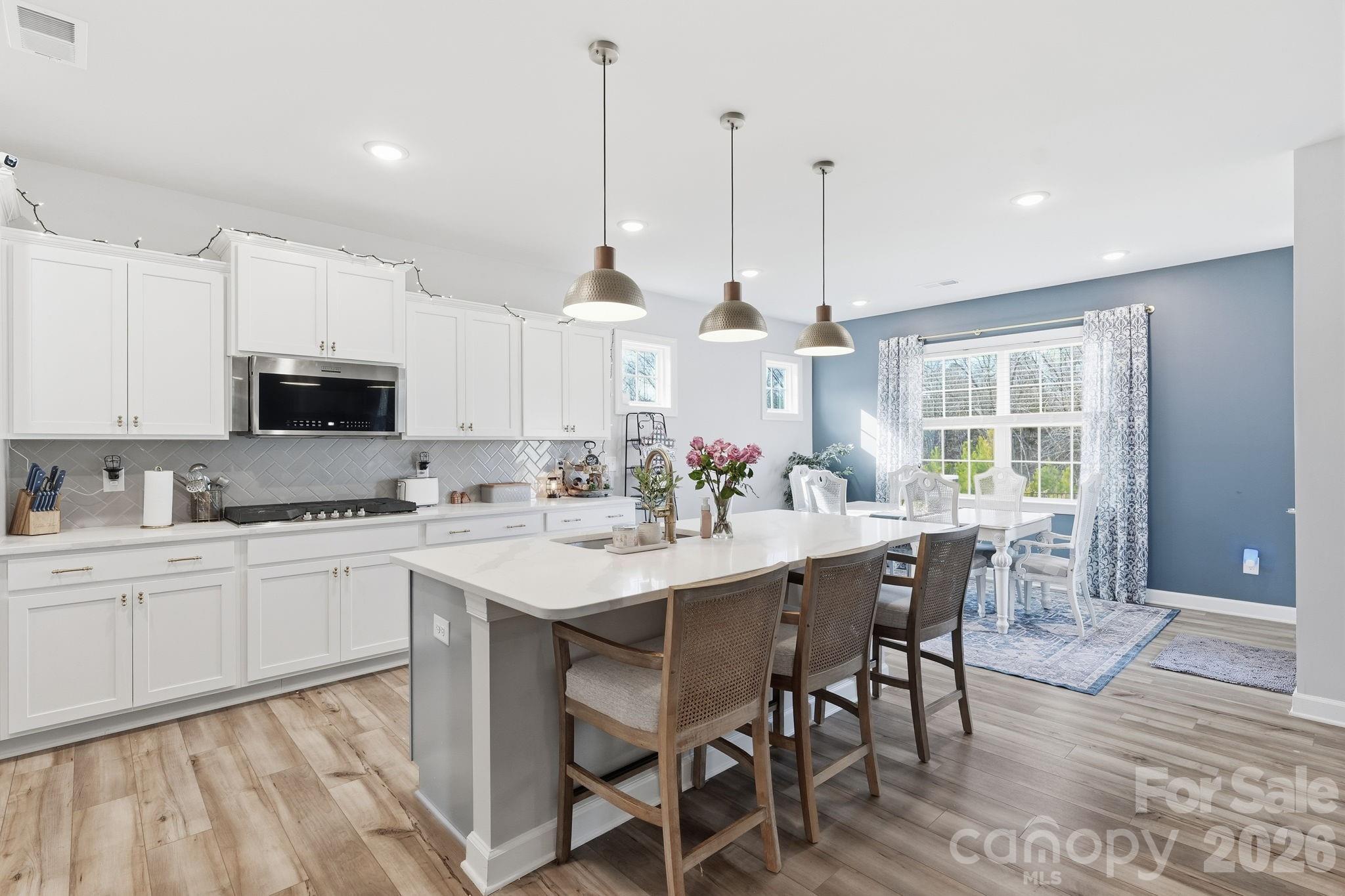3911 Horsham Street Fort Mill, SC 29707 - Photo 3 of 41 a kitchen with stainless steel appliances granite countertop a stove a sink a microwave a dining table and chairs