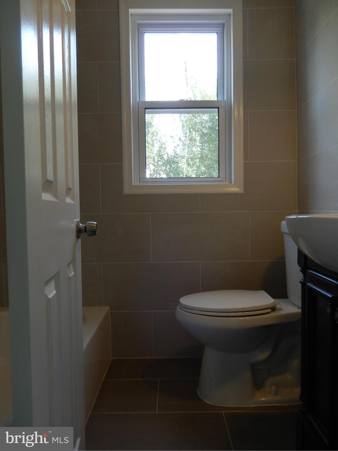 4301 Cedar Garden Road Baltimore, MD 21229 - Photo 11 of 29 a white toilet sitting in a bathroom next to a window