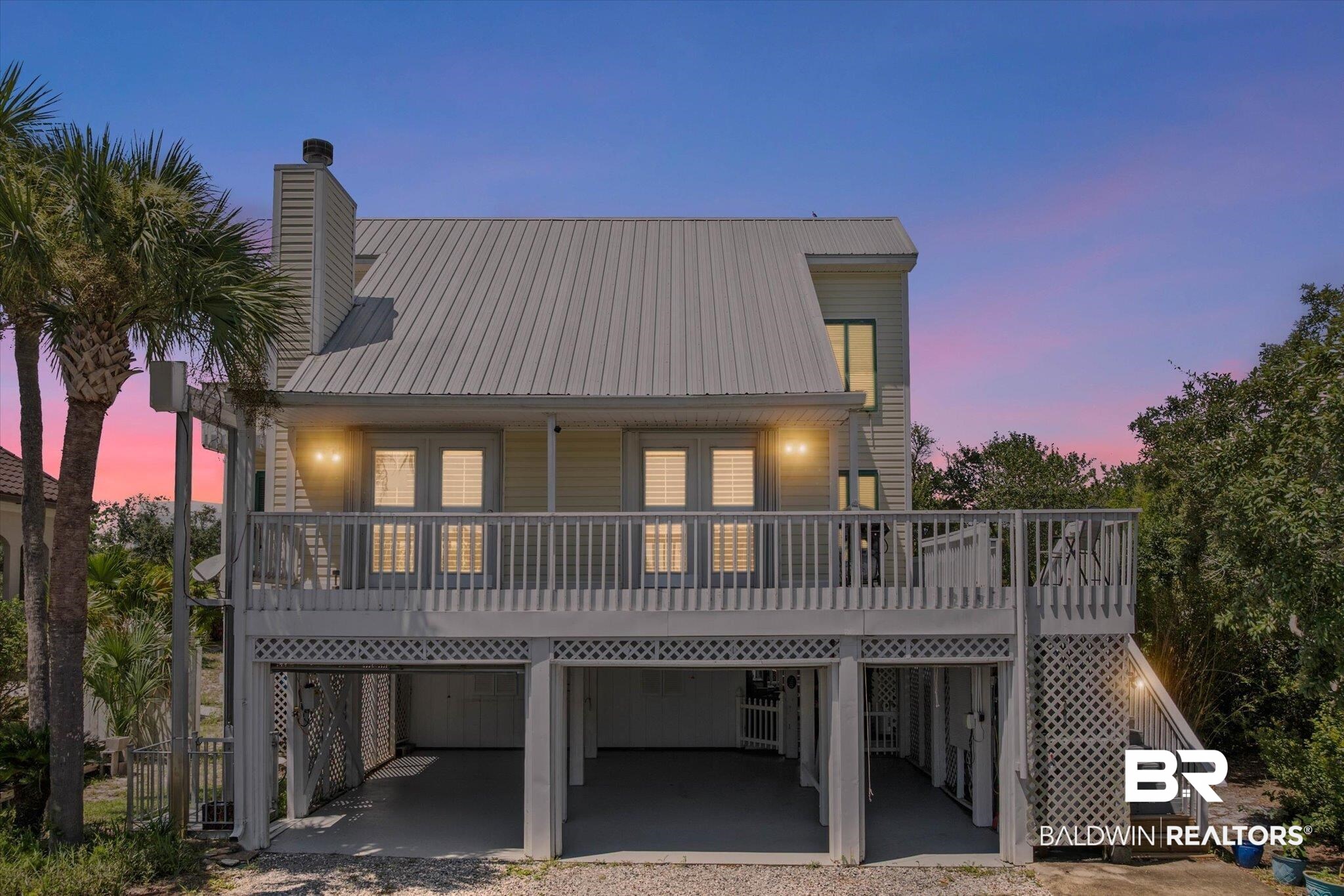 Rear view of property with a carport, stairs, a chimney, a deck, and a metal roof