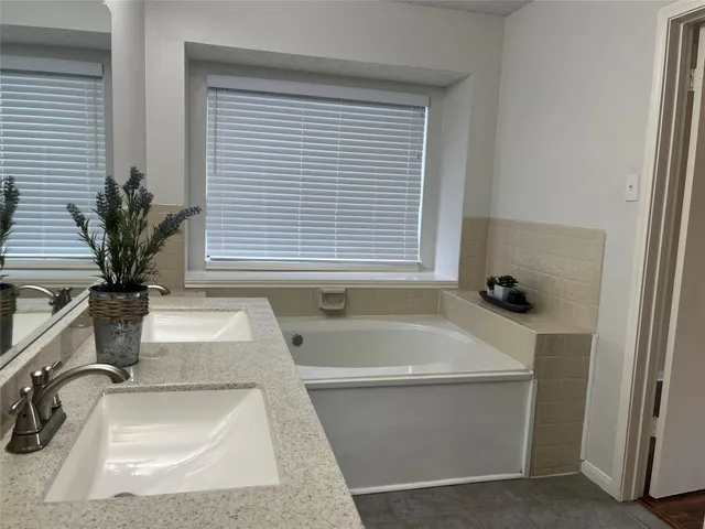 a bathroom with a tub a sink and a window