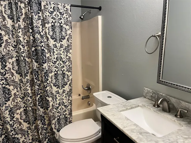 a bathroom with a granite countertop sink toilet and shower