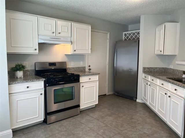 a kitchen with granite countertop white cabinets and stainless steel appliances