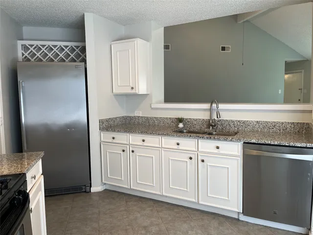 a kitchen with granite countertop white cabinets and a sink