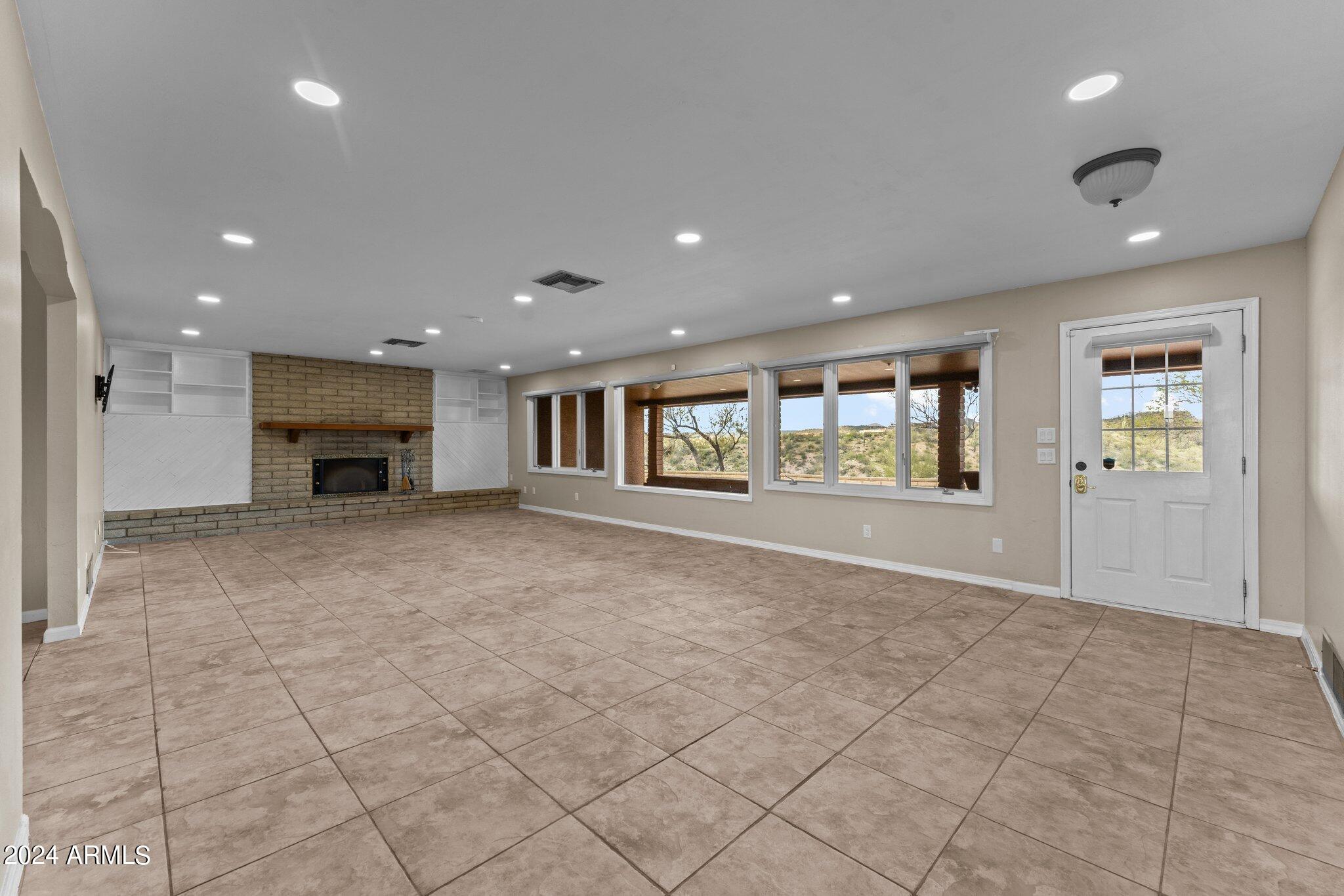 1605 North Little Stonehedge Ranch Road Wickenburg, AZ 85390 - Photo 11 of 54 a view of an empty room with a fireplace and a window