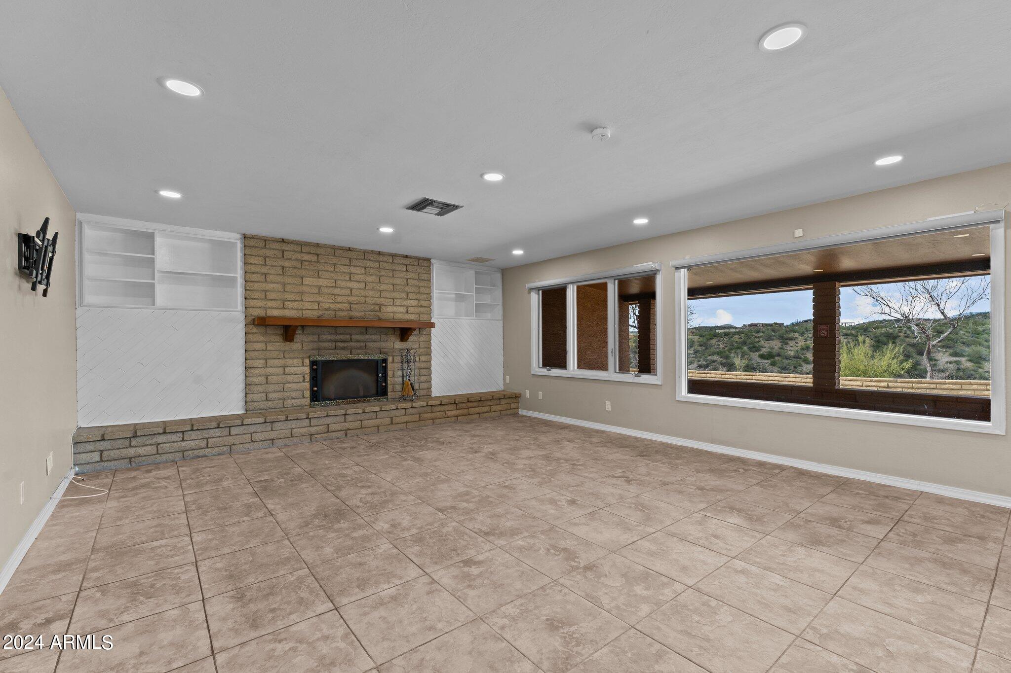 1605 North Little Stonehedge Ranch Road Wickenburg, AZ 85390 - Photo 12 of 54 a view of an empty room with a fireplace and a window