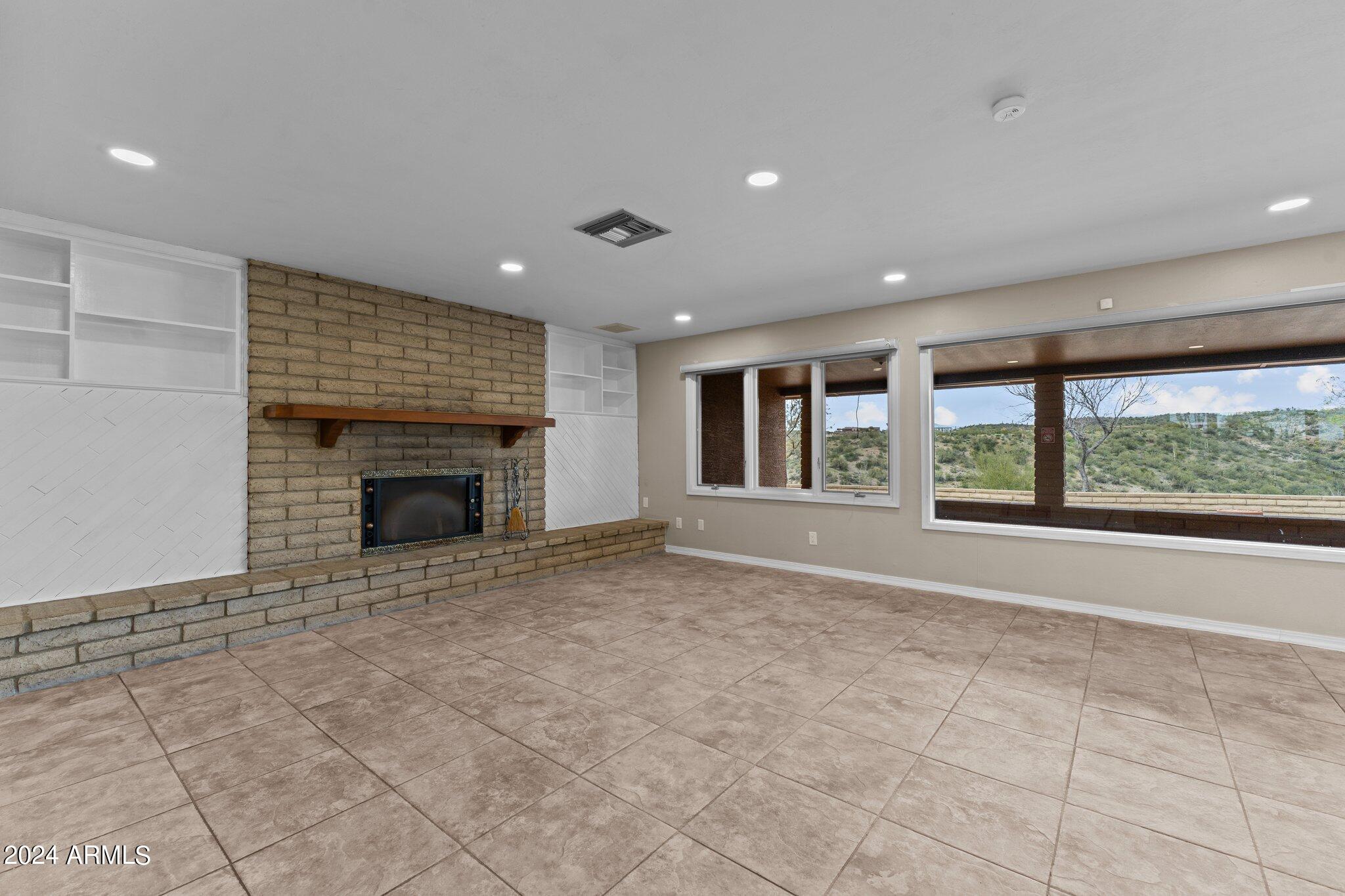 1605 North Little Stonehedge Ranch Road Wickenburg, AZ 85390 - Photo 13 of 54 a view of an empty room with a fireplace and a window