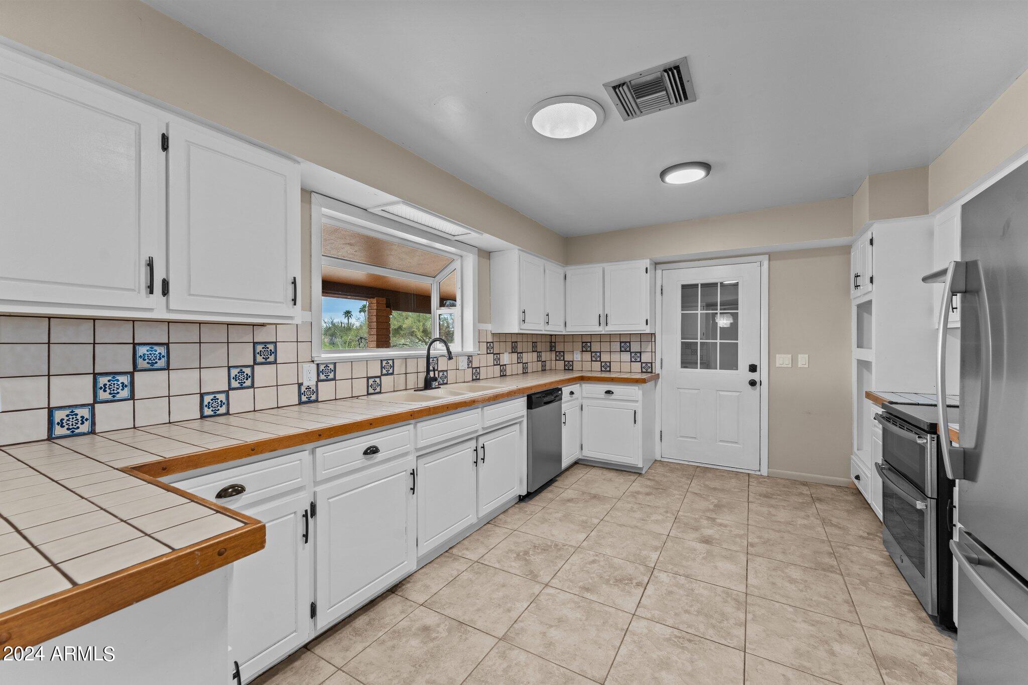 1605 North Little Stonehedge Ranch Road Wickenburg, AZ 85390 - Photo 7 of 54 a large kitchen with white cabinets and stainless steel appliances