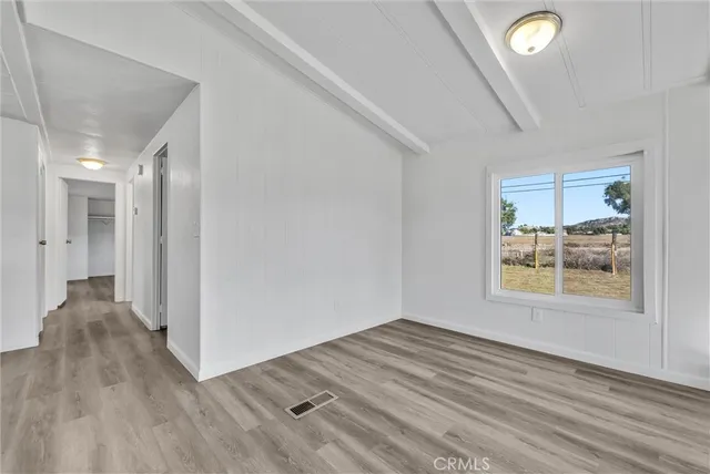a view of empty room with wooden floor and kitchen view