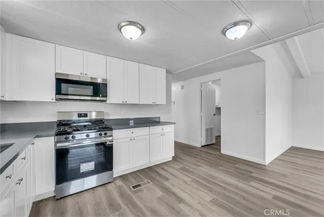 a kitchen with granite countertop a refrigerator stove top oven and sink