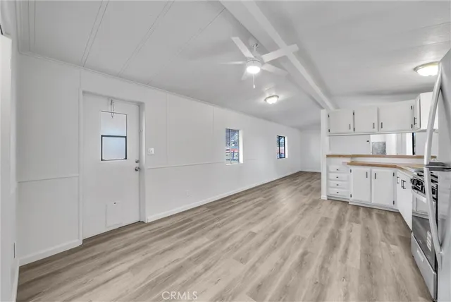 a kitchen with granite countertop a refrigerator oven a sink dishwasher and white cabinets with wooden floor