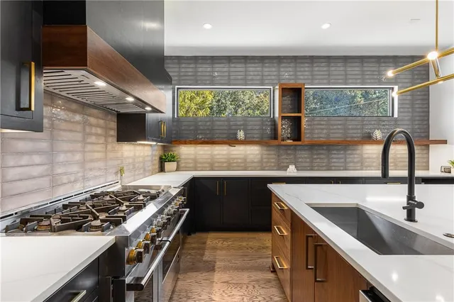 a kitchen with stainless steel appliances granite countertop a sink a stove and a wooden floor