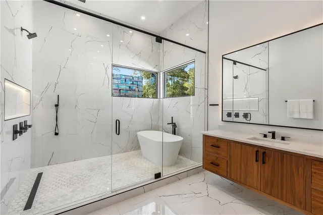 a bathroom with a tub a sink and glass door shower
