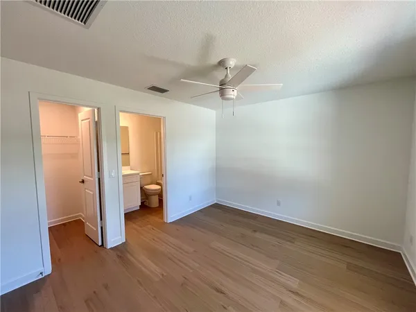 an empty room with wooden floor fan and windows