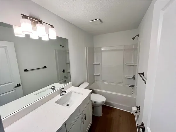 a bathroom with a bathtub shower sink mirror and toilet